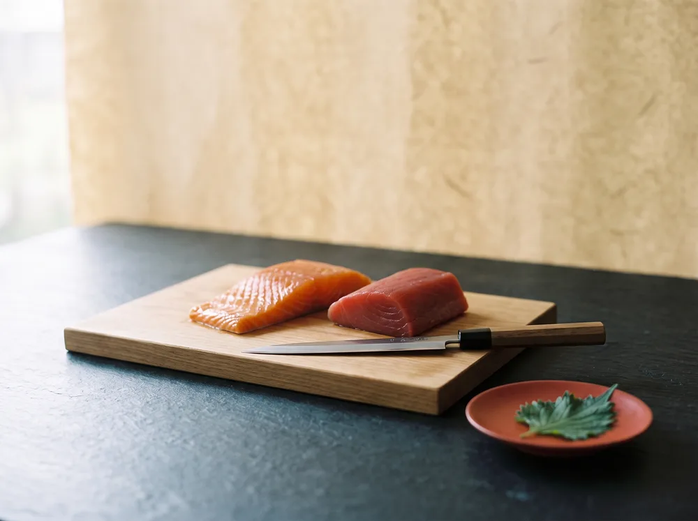 Frischer Lachs und Thunfisch mit Yanagiba-Messer auf dem Schneidebrett